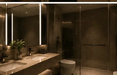 A hotel bathroom with a backlit mirror and stone surfaces